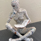 Lesende Figur aus Kunstharz mit Zeitungsdruck-Optik Zorenza