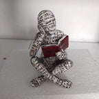 Lesende Figur aus Kunstharz mit Zeitungsdruck-Optik Zorenza
